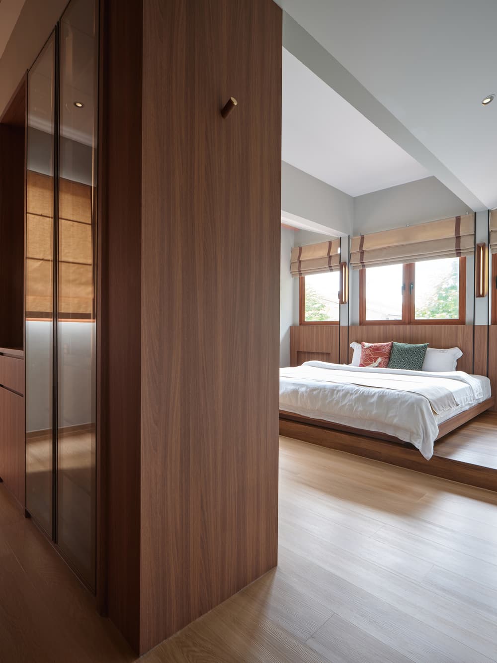 The bedroom seen past the timber wardrobe screen at A Sensory House, a luxury landed house interior in Singapore by K2SD Group