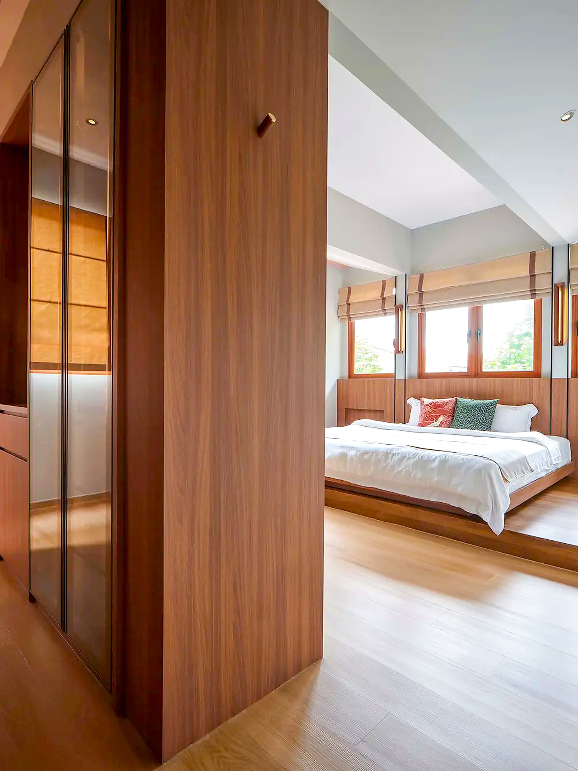 The bedroom seen past the timber wardrobe screen at A Sensory House, a luxury landed house interior in Singapore by K2SD Group