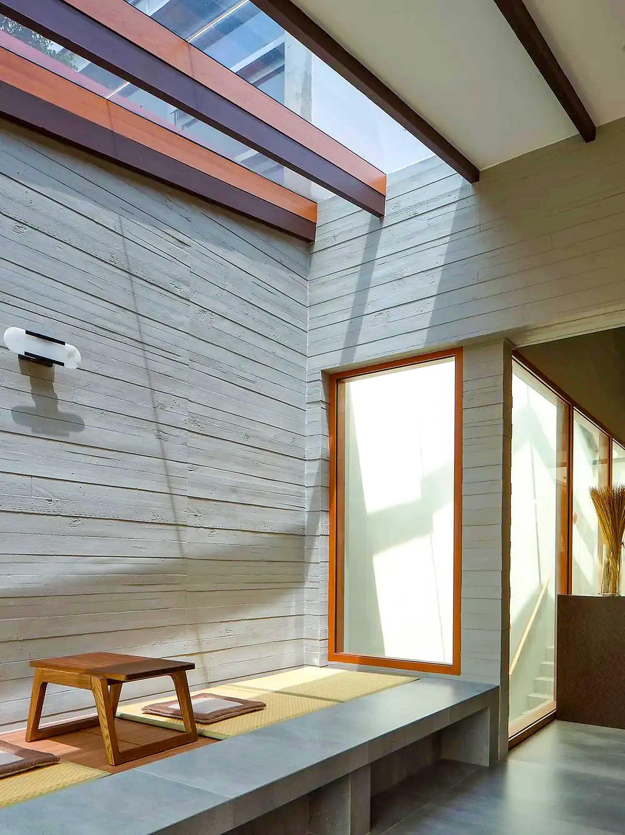 Light across the board marked concrete wall above the tatami platform at A Sensory House, a luxury landed house interior in Singapore by K2SD Group